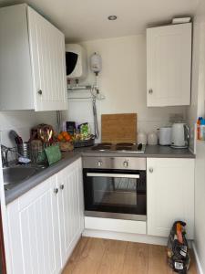 a kitchen with white cabinets and a black oven at River Cabin Retreat in Shepperton