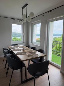 a dining room with a table and chairs and windows at Apartamenty Sznurki in Sznurki