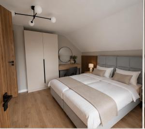 a bedroom with a large white bed and a mirror at Apartamenty Sznurki in Sznurki