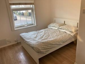 a small bedroom with a bed with a window at Chestnut Villa in Epsom