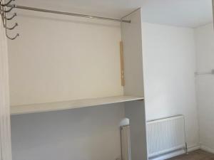 a white room with a shelf on a wall at Chestnut Villa in Epsom