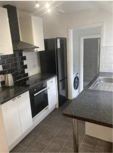 a kitchen with white cabinets and a black appliances at Chestnut Villa in Epsom
