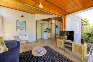 a living room with a blue couch and a television at Comfortable chalet in a vacation village in Gujan-Mestras