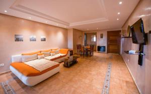 a living room with a couch and a flat screen tv at Spacious apartment, pool, beach, basement parking in Bouznika