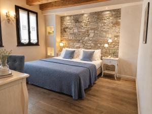 a bedroom with a bed and a stone wall at Casa Delneri Boutique Hotel Adults Only in Aquiléia
