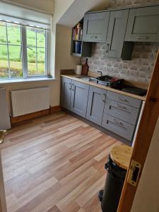 a kitchen with white cabinets and a wooden floor at Apartment in Coolea in Bard Inch