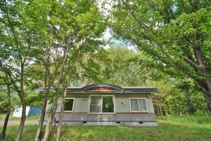 a house with trees in front of it at 民宿やまのほ in Engaru
