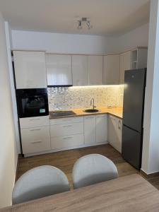 a kitchen with two chairs and a sink and a refrigerator at Apartman 38 in Stara Pazova +9 photos