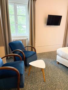 a room with two chairs and a bed and a tv at Logis Hôtel Du Château - Combourg, Proche Saint-Malo in Combourg