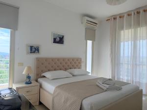 a white bedroom with a bed and a window at Sunrise Apartment Qerret in Kavajë +13 photos