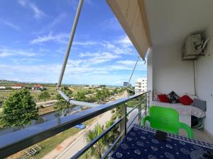 a balcony with a green chair and a bed at Sunrise Apartment Qerret in Kavajë
