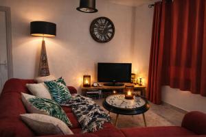 a living room with a red couch and a clock on the wall at La Kaz Sumac in Saint-Pierre