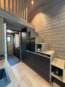 a kitchen with black appliances and a wooden wall at Bjørgo Gard - Stegastein in Aurland