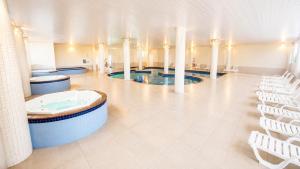 a large room with three jacuzzi pools and white chairs at THE - Tropicanas Hotel e Eventos in Florianópolis
