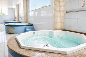 a large bath tub with blue water in a bathroom at THE - Tropicanas Hotel e Eventos in Florianópolis