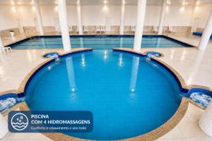 a large swimming pool with blue water in a building at THE - Tropicanas Hotel e Eventos in Florianópolis