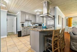 a kitchen with white cabinets and a island with bar stools at Saint Johns Oasis - Pool Hot Tub Grill in Jacksonville