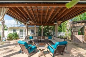 a patio with a couch and chairs under a wooden pergola at Saint Johns Oasis - Pool Hot Tub Grill in Jacksonville