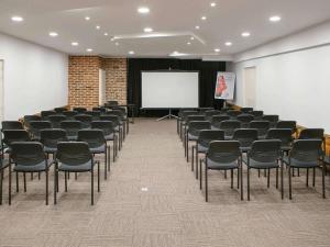 a room with chairs and a whiteboard and a screen at ibis Douai Centre in Douai