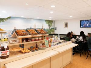 a cafeteria with a counter with food and people sitting at ibis Styles Caen Centre Historique in Caen