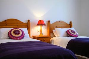 a bedroom with two beds and a lamp on a table at La Casita Azul in Punta de Mujeres