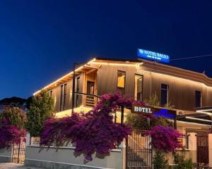 a hotel with purple flowers in front of a building at Hotel Balili in Vlorë