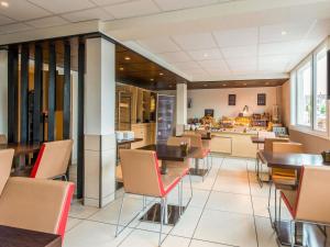 a restaurant with tables and chairs and a kitchen at Hôtel Ibis Cognac Centre in Cognac