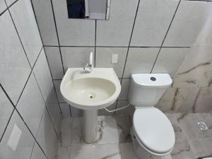 a white bathroom with a toilet and a sink at Hotel Goldem Park in Brasília