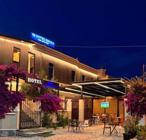 a hotel with tables and chairs outside of it at night at Hotel Balili in Vlorë