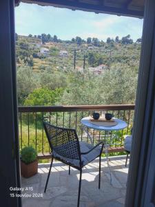 a table and chair on a balcony with a view at Dafnes in Skopelos Town