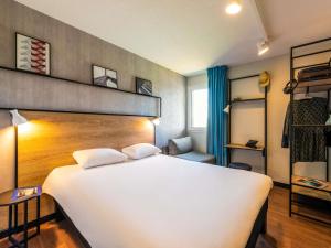 a bedroom with a large white bed and a chair at ibis Besançon Marchaux in Marchaux