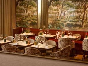 a restaurant with tables and chairs and a painting at Grand Hôtel Roi René Aix - MGallery Collection in Aix-en-Provence