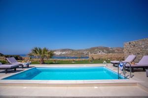a swimming pool in a yard with chairs at South Star private Mini Villa in Mikonos
