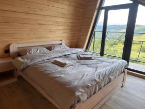 a bed in a wooden room with a large window at Barnhouse VOLOVETS in Volovets