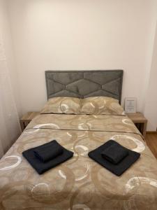 a bed with two black towels on top of it at Taca 1 - Airport apartman in Surčin