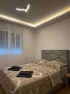 a bedroom with a bed with two black towels on it at Taca 1 - Airport apartman in Surčin