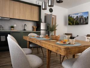 a kitchen and dining room with a wooden table and chairs at Apartmán u Fary-Harmony in Adršpach