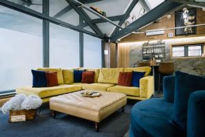 a living room with a yellow couch and blue chairs at Architect's Loft in Windermere