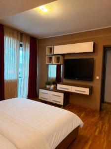 a bedroom with a large bed and a flat screen tv at King Apartment Bucharest in Dudu +3 photos