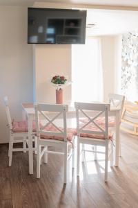 a white dining room table with two chairs and a television at Róna Fénye Vendégház in Sándorfalva