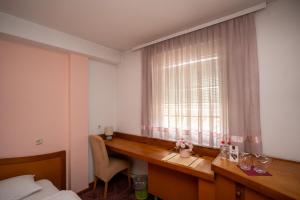 a bedroom with a desk and a window with a window treatment at Hotel Ferijalac in Sarajevo
