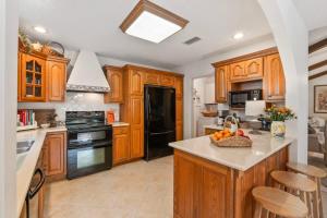 a kitchen with wooden cabinets and a black refrigerator at Sherylee's Poolside Retreat - Team Joseph Ellen in Jacksonville