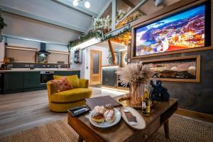 a living room with a table and a large tv at Queen's Loft in Windermere