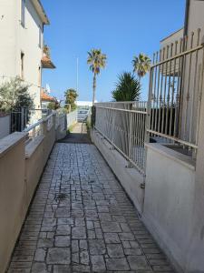 a stone walkway with a fence and palm trees at Casa Alma in Lido di Fermo +5 photos