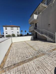 a house with a stone driveway in front of a building at Casa Alma in Lido di Fermo