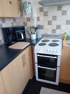 a kitchen with a white stove and a microwave at Owls Roost in Stowmarket +4 photos