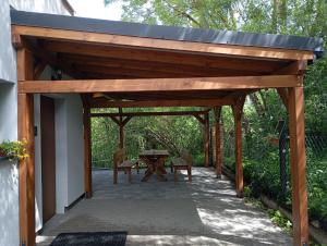 a wooden pergola with a table and chairs on a patio at Pokoje przy rzece in Supraśl