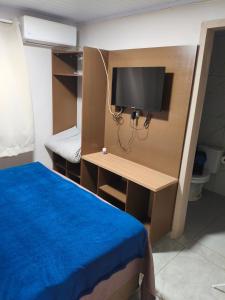 a room with a bed and a desk with a tv at Recanto Coração da Ametista - Apart hotel & Suítes in Ametista do Sul