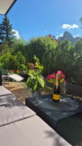 a table with a bottle of wine and flowers on it at Ammergaufeeling mit einmaligem Bergblick, Terrasse, Nähe zur Nato Schule in Oberammergau