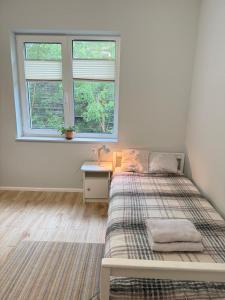 a bedroom with a bed and a desk and two windows at Pokoje przy rzece in Supraśl